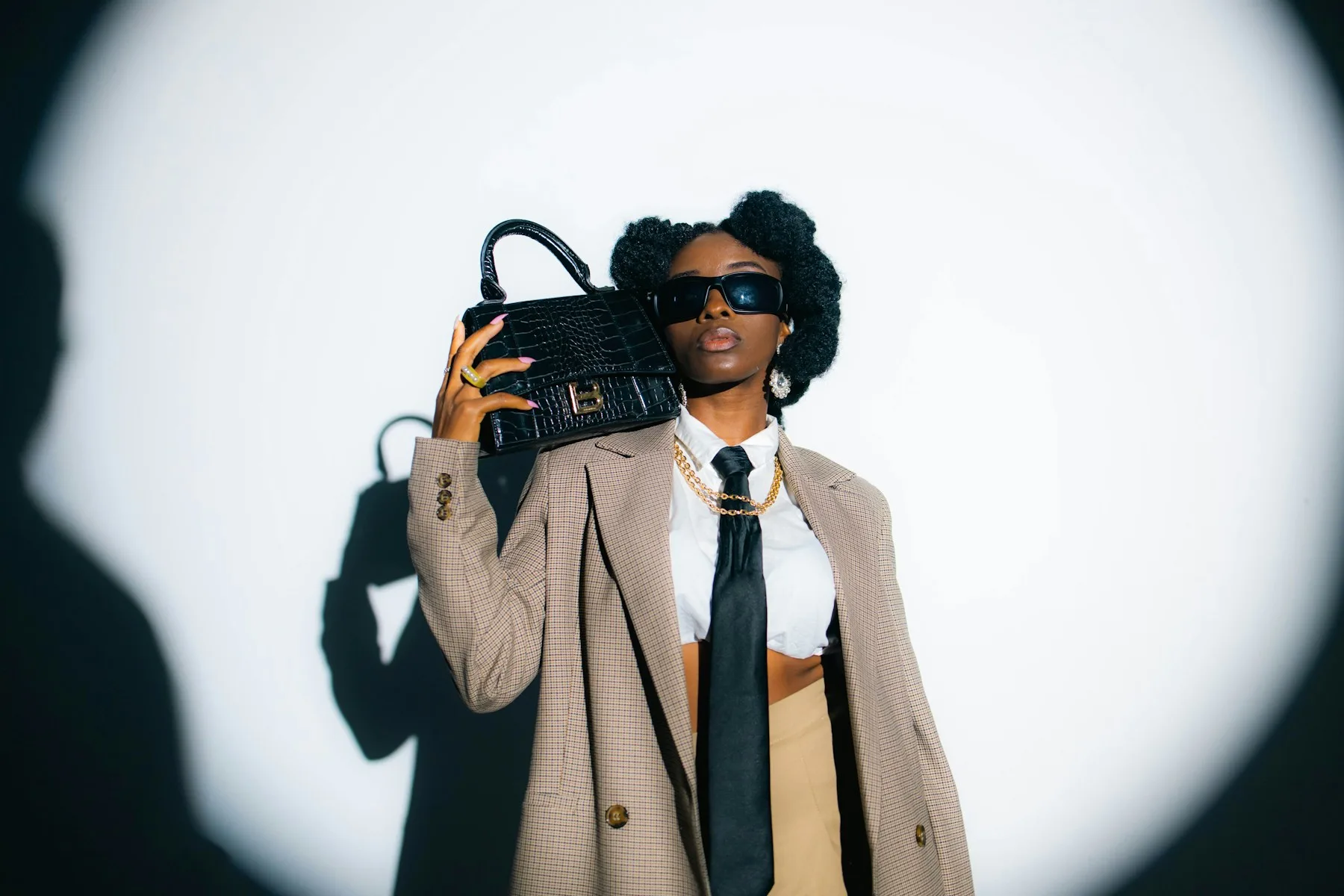 A fashion model in a tailored jacket holding a black handbag