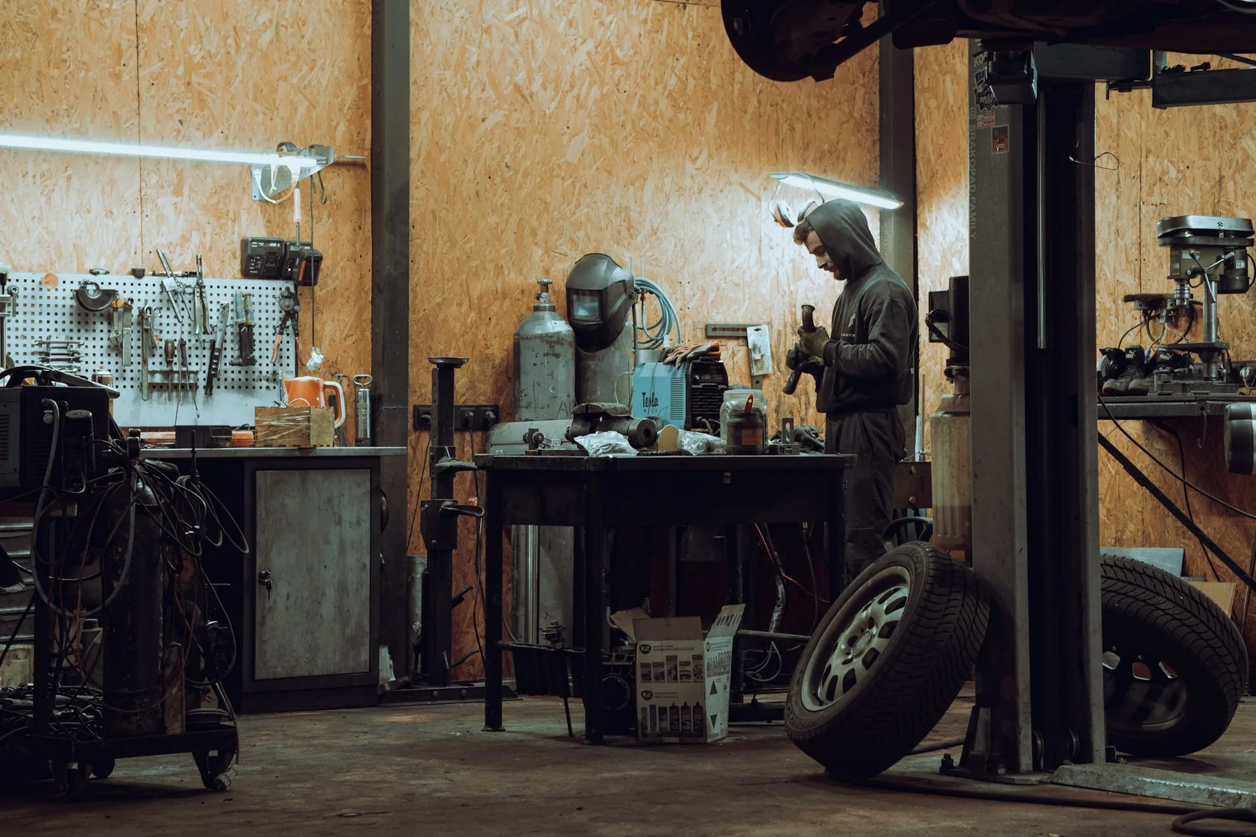 A mechanic working at a bench in a warm, tool-filled automotive workshop
